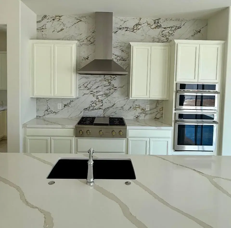 Detail of a custom kitchen remodel with white quartz waterfall counter and full-height quartz backsplash, stainless gas cooktop, double wall oven, and undermount sink by Zona Floors